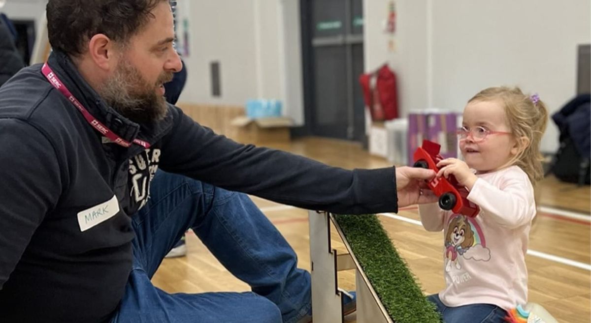 Man and small child holding a small toy car.